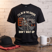 Load image into Gallery viewer, I'll Be In The Garage, Don't Wait Up skeleton t-shirt standing on a workbench with a trucker cap, mug and socket wrench