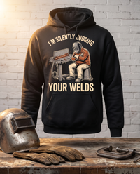 Load image into Gallery viewer, I'm Silently Judging Your Welds welder hoodie on a workbench with a welding helmet, gloves and C-clamp