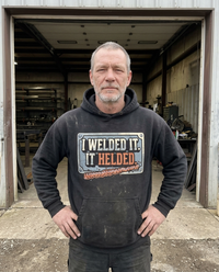 Load image into Gallery viewer, Welder wearing the I Welded It It Helded hoodie outside his shop